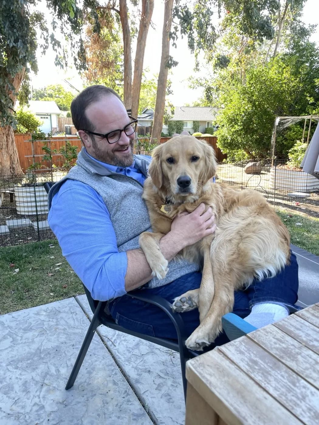 Kevin Roche sitting in his garden holding Moose, his Golden Retriever